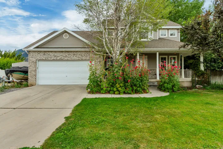 Traditional home exterior featuring a front porch with white columns, a two-car garage, and a concrete driveway