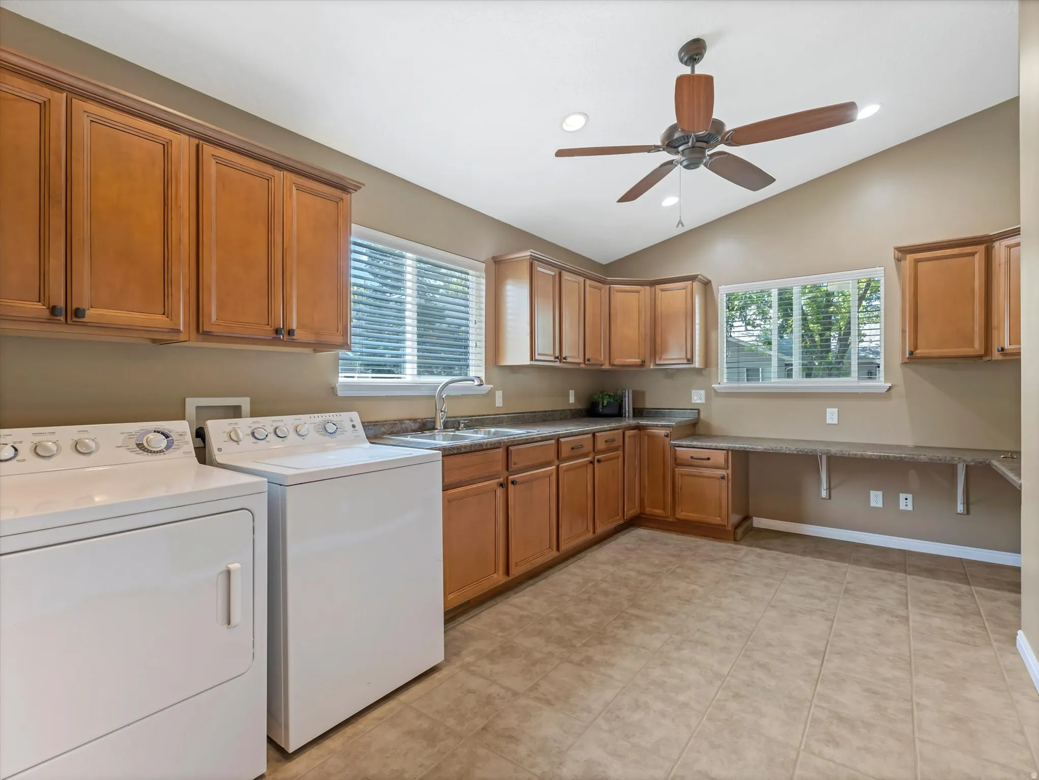 Spacious utility/ laundry room featuring extensive wood cabinetry, a utility sink with a chrome faucet, and ample counter space