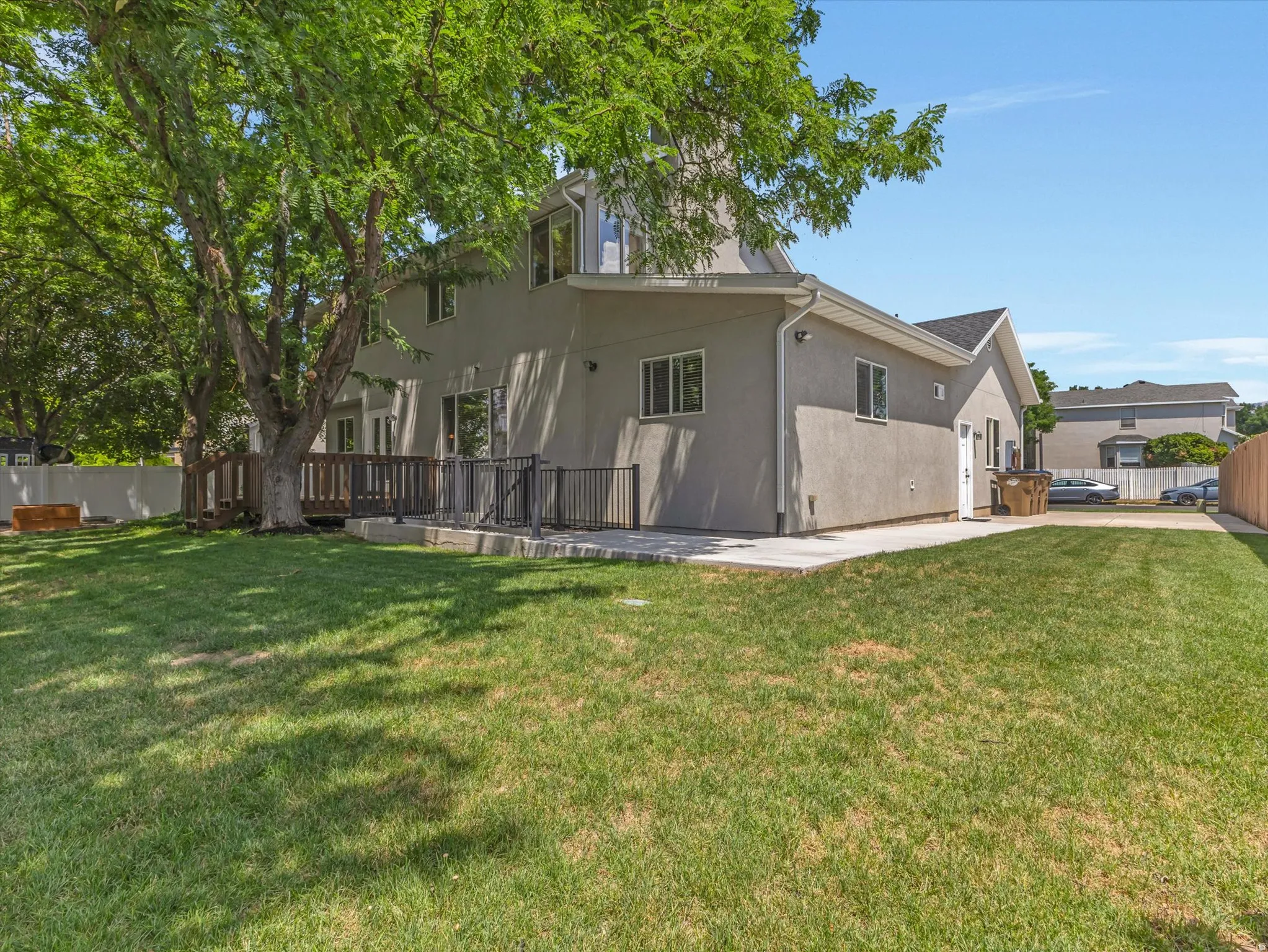 Spacious backyard featuring a substantial lawn, mature tree, and a multi-level deck