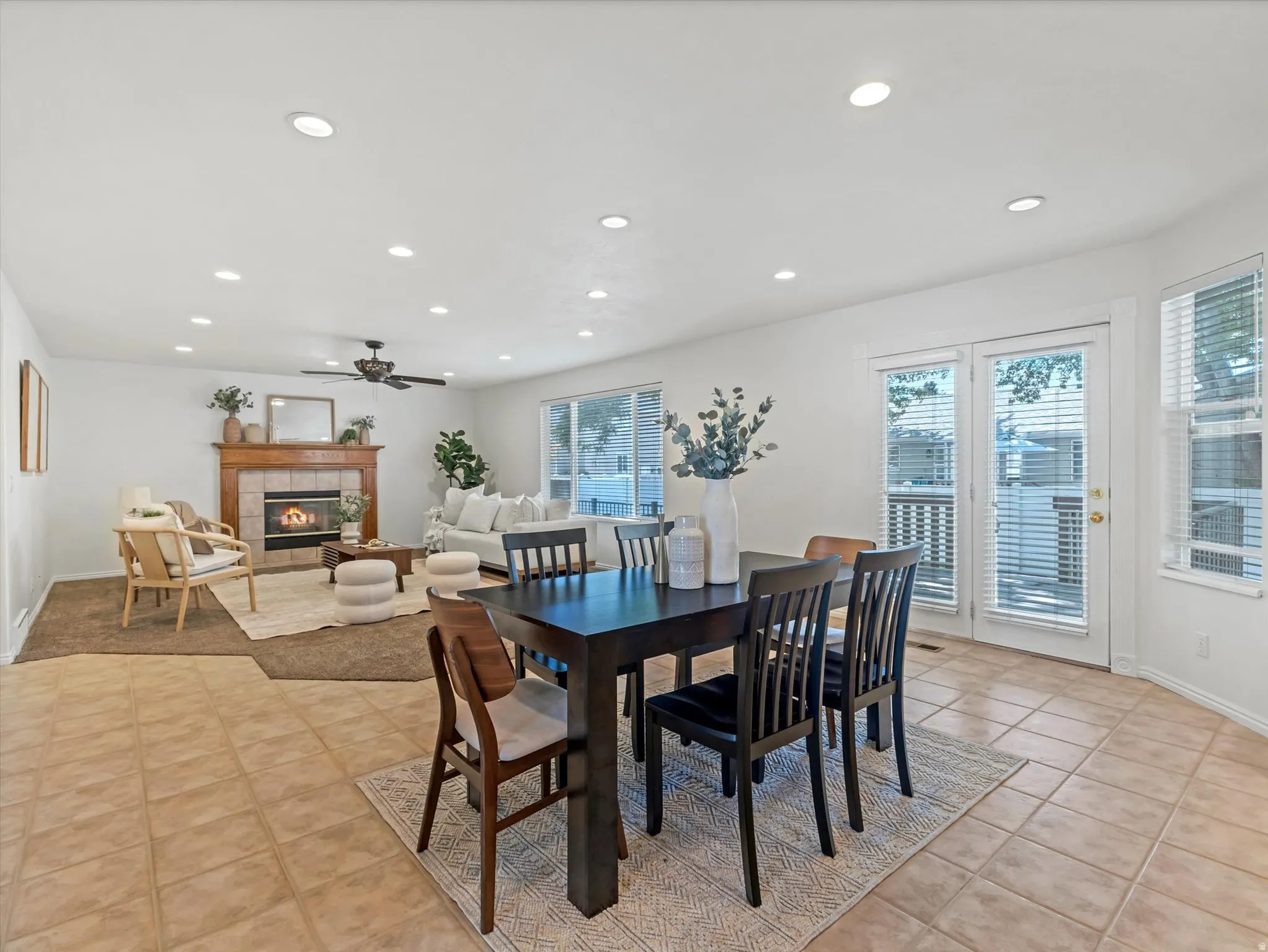 Open-concept living area featuring a tile fireplace with a wood mantle, recessed lighting, and a ceiling fan