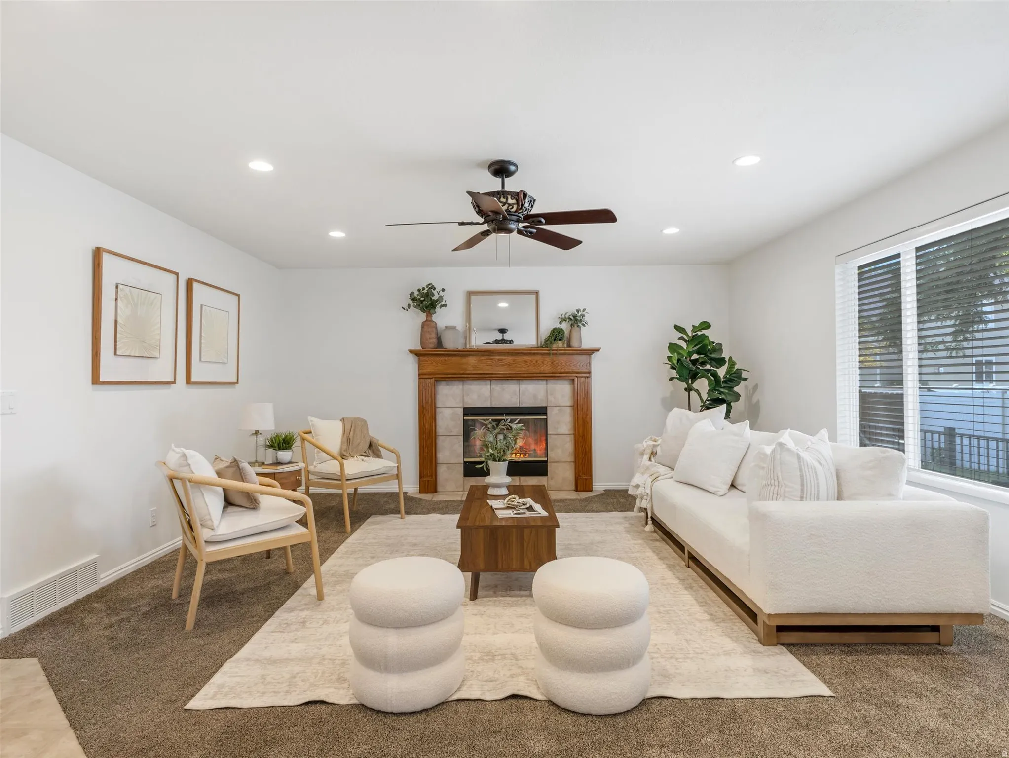 Living space featuring a tiled fireplace with wood mantel, recessed lighting, and a ceiling fan