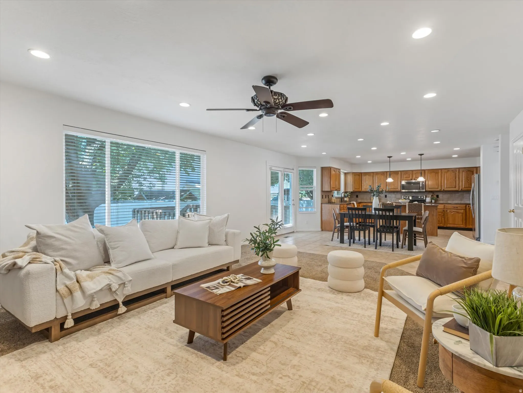 Open concept living area with recessed lighting, a ceiling fan, and large windows