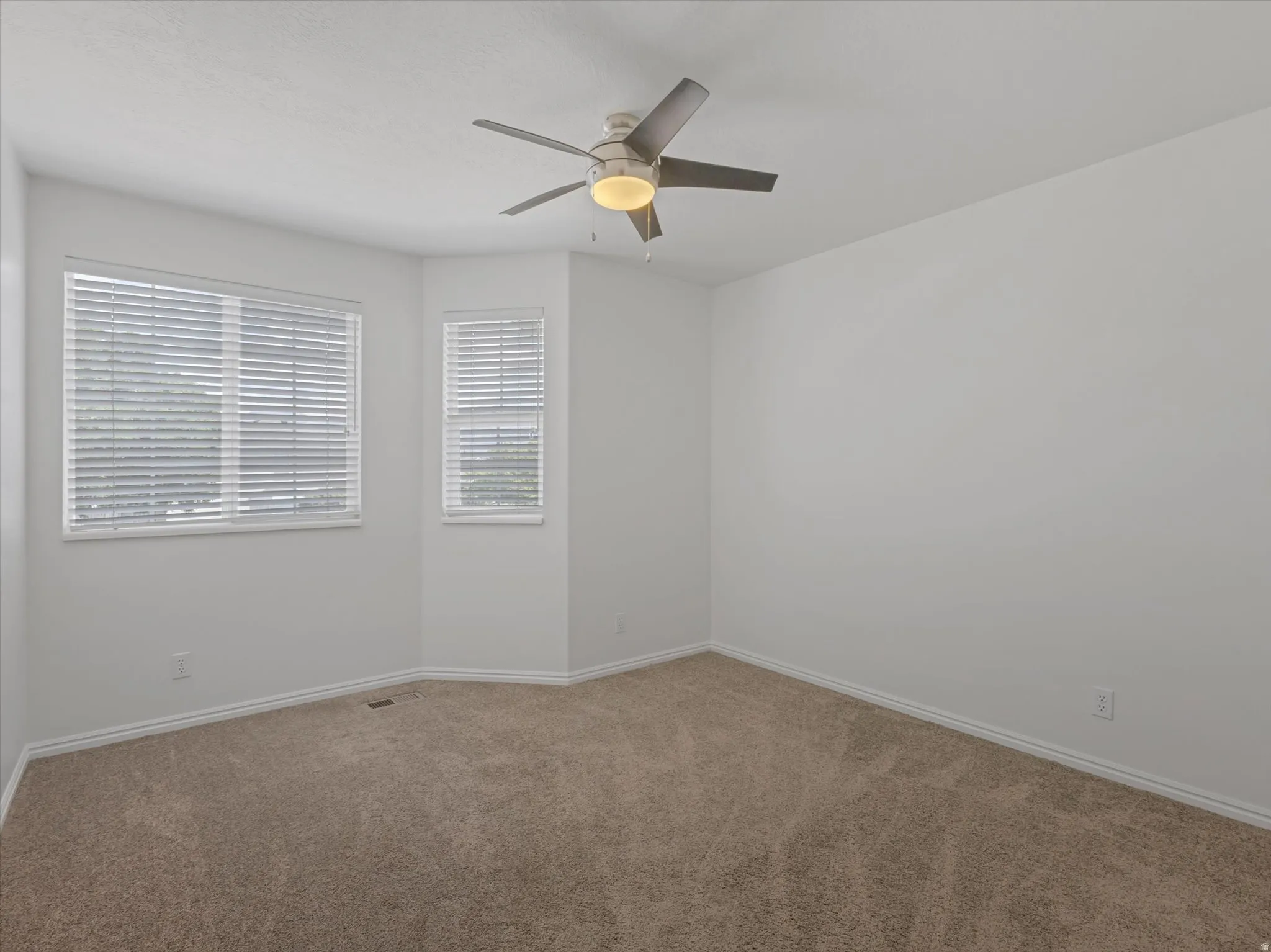Bedroom 4-Carpeted room featuring a ceiling fan with integrated lighting, multiple windows with blinds, and white baseboards