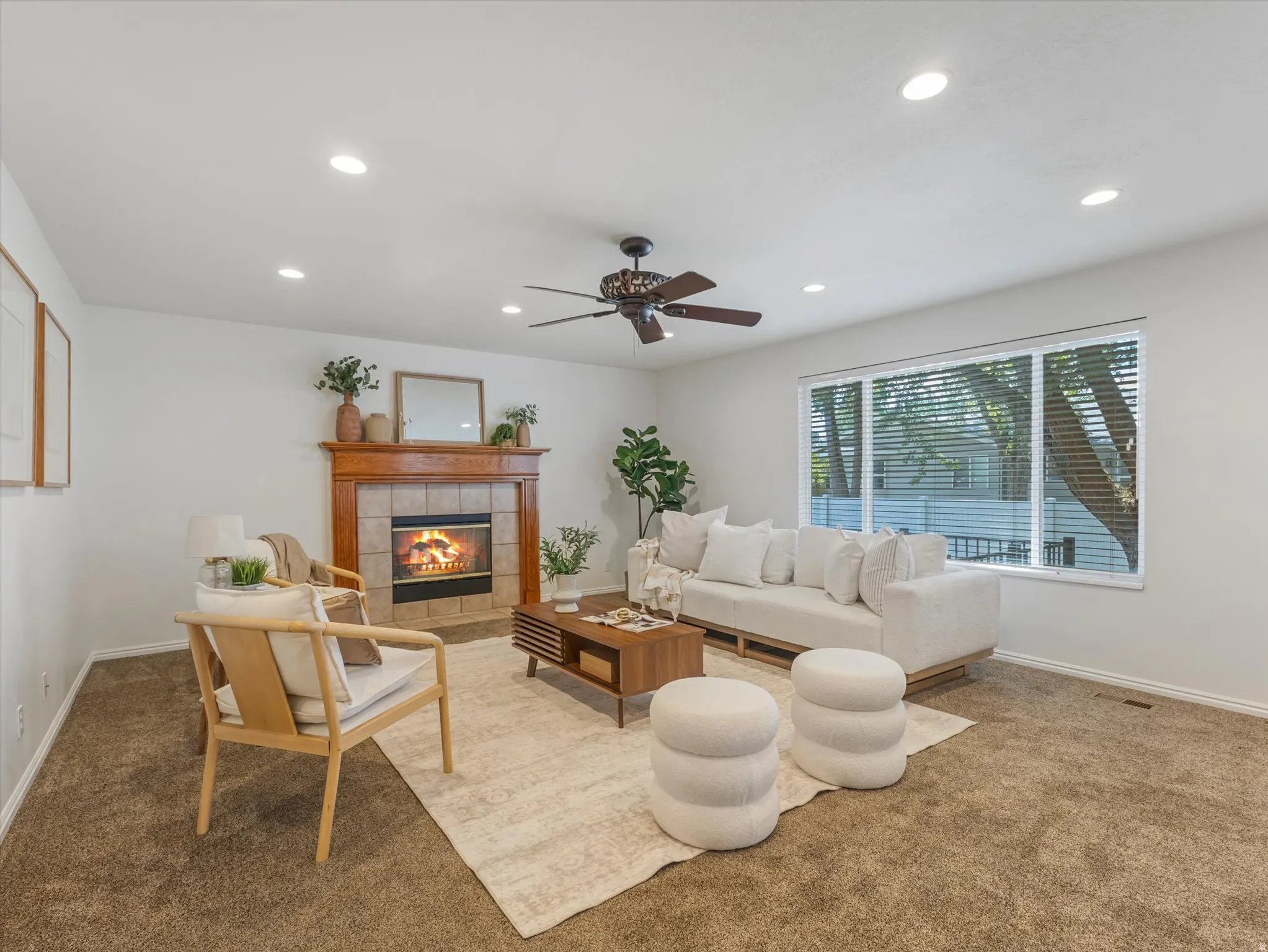 Spacious living area featuring a tile-surround fireplace with a wood mantle, recessed lighting, and a ceiling fan