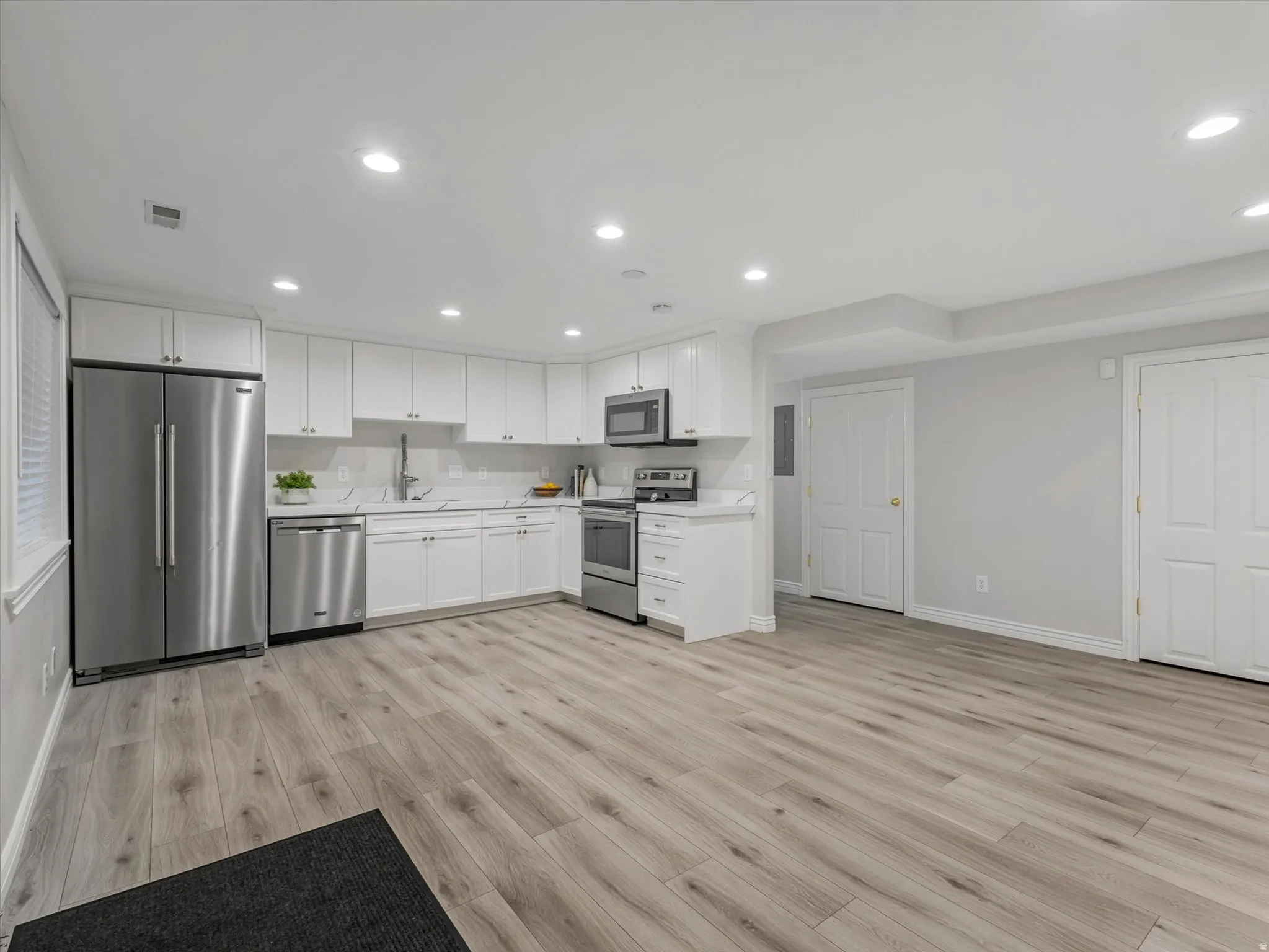 Spacious 2nd Kitchen area /ADU with separate entrance, featuring white cabinetry, stainless steel appliances, light-toned wood-finish flooring, recessed lighting, and white countertops