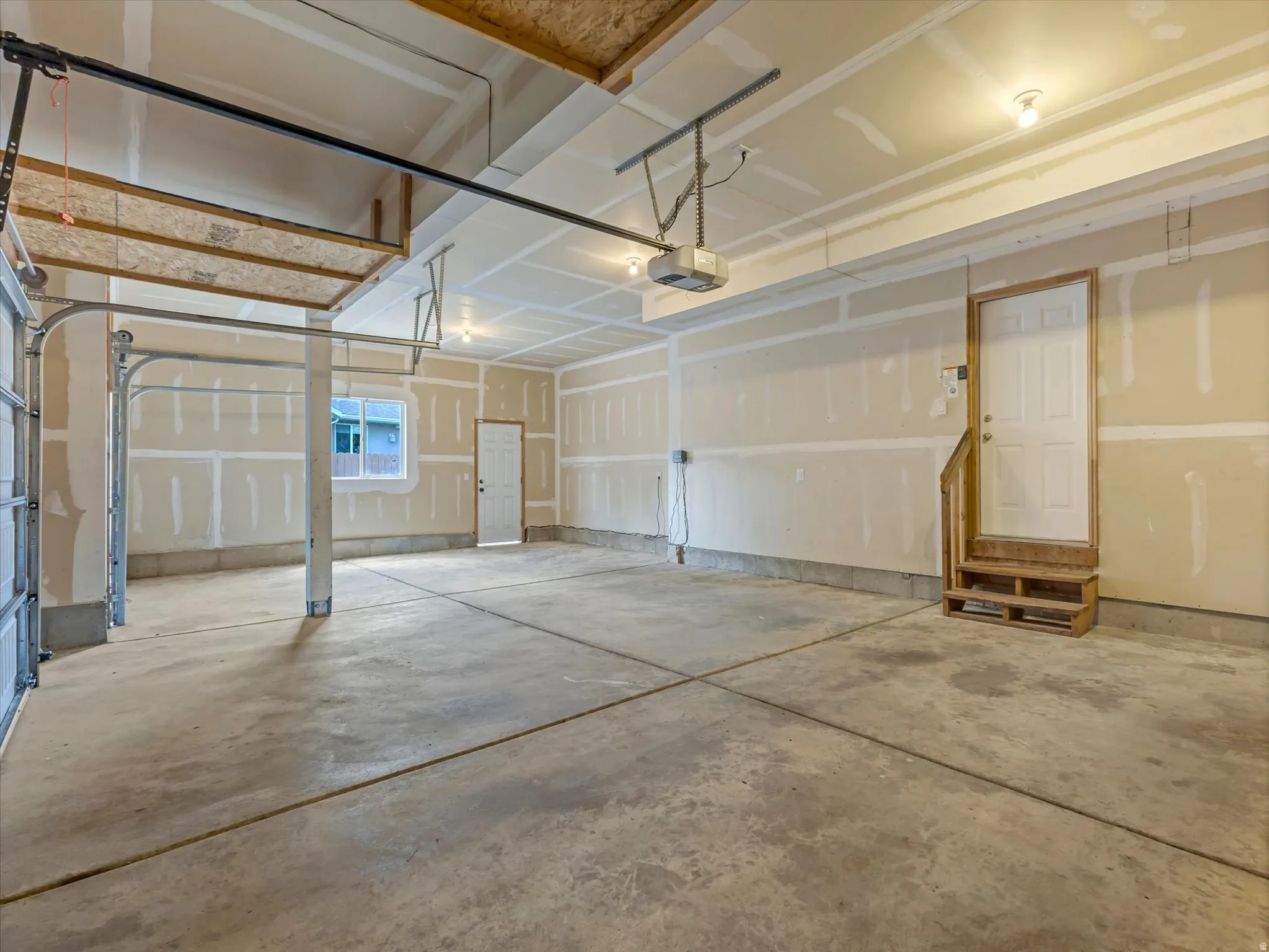 Spacious garage featuring concrete flooring and exposed ceiling rafters