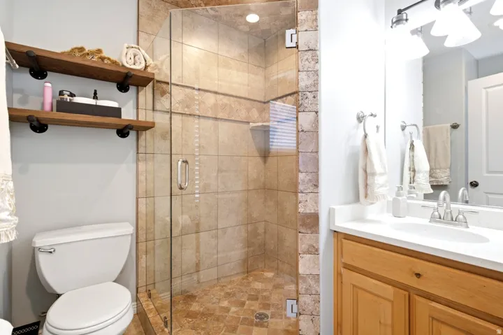Walk-in shower with clear glass enclosure and stone-look tile surround