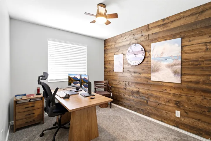 bedroom/office space featuring a prominent wood-panel accent wall and light gray wall paint