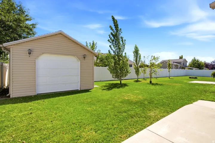 Shed with a garage door and newly planted trees for privacy.