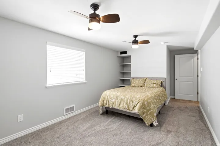 Carpeted interior space featuring light gray walls, white baseboards, and two ceiling fans with light fixtures