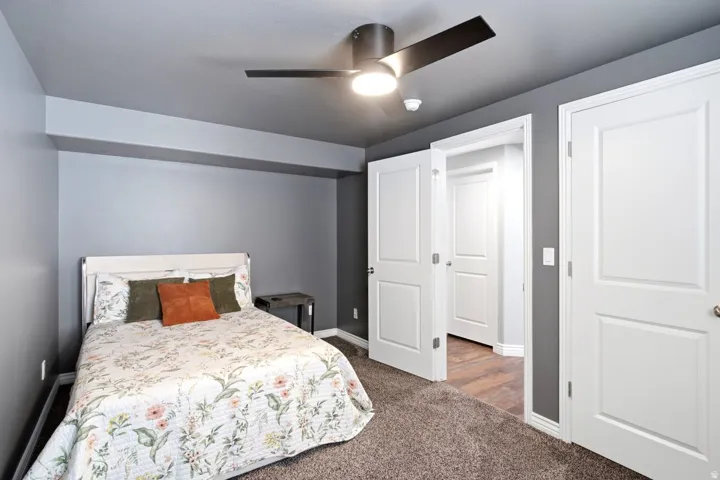 Bedroom with a modern ceiling fan, gray painted walls, and brown carpet flooring