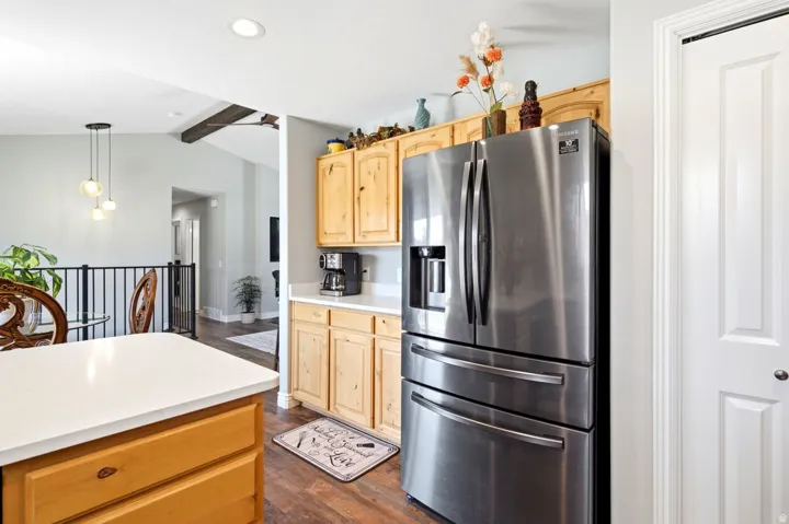 Kitchen featuring light wood cabinetry, white countertops, wood-finish flooring, and a stainless steel refrigerator