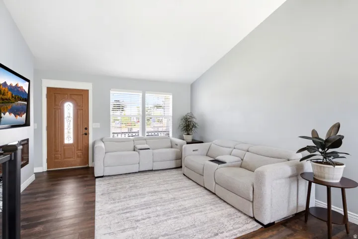 Inviting living area featuring rich wood-finish flooring, a decorative front entry door with an arched glass insert, and large windows providing abundant natural light