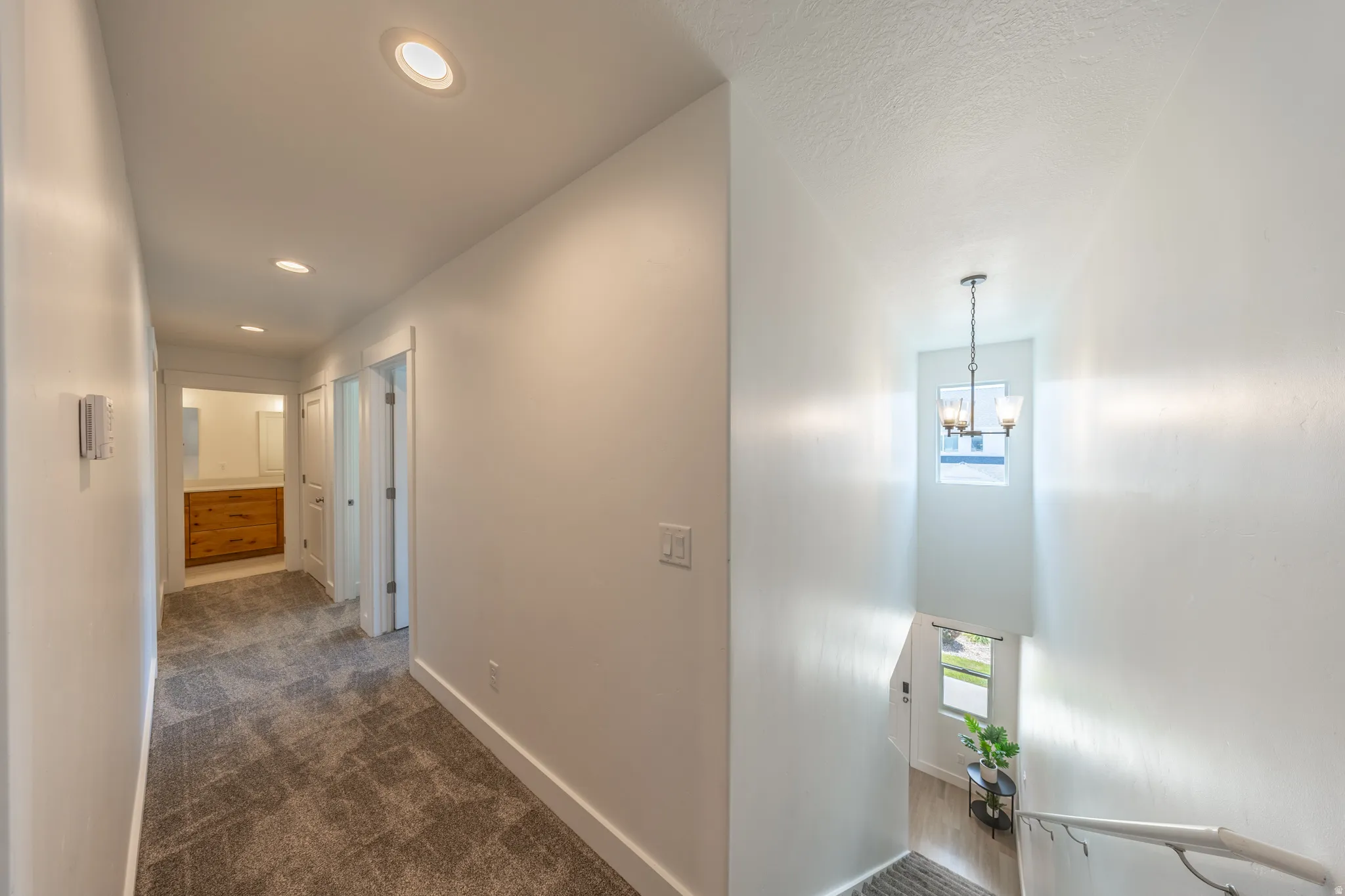 Upper-level hallway with recessed lighting and gray patterned carpet