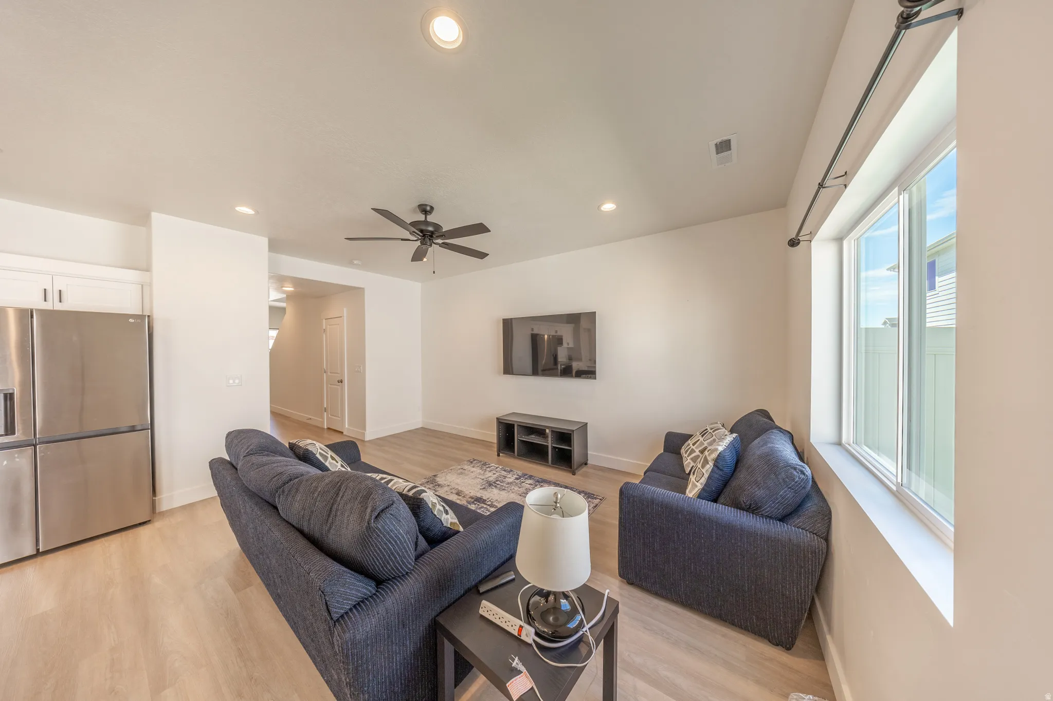 Open-concept living area with wood-finish flooring, recessed lighting, and a ceiling fan