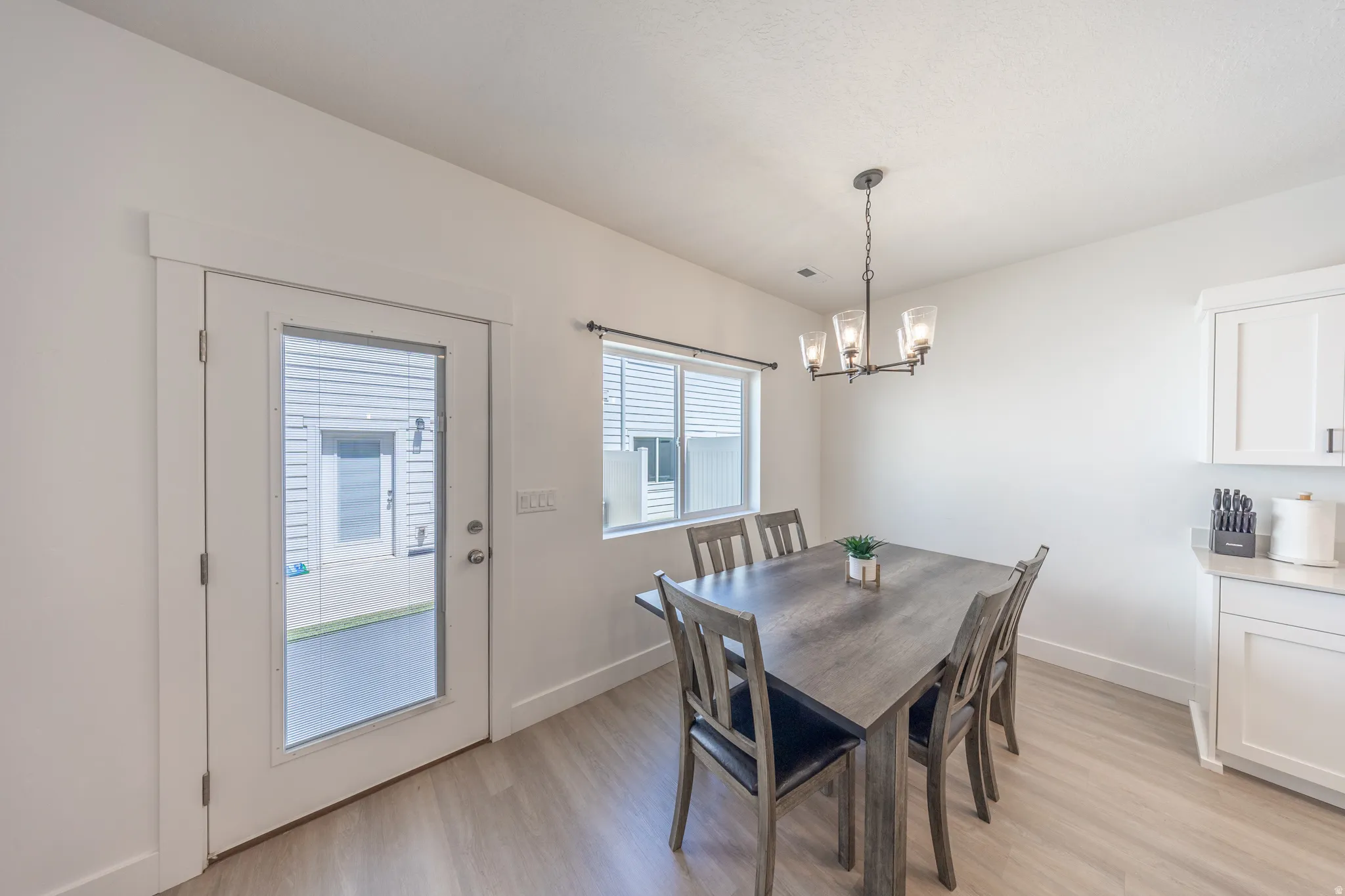 Dining area featuring wood-finish flooring, a contemporary chandelier, and a glass-paned exterior door