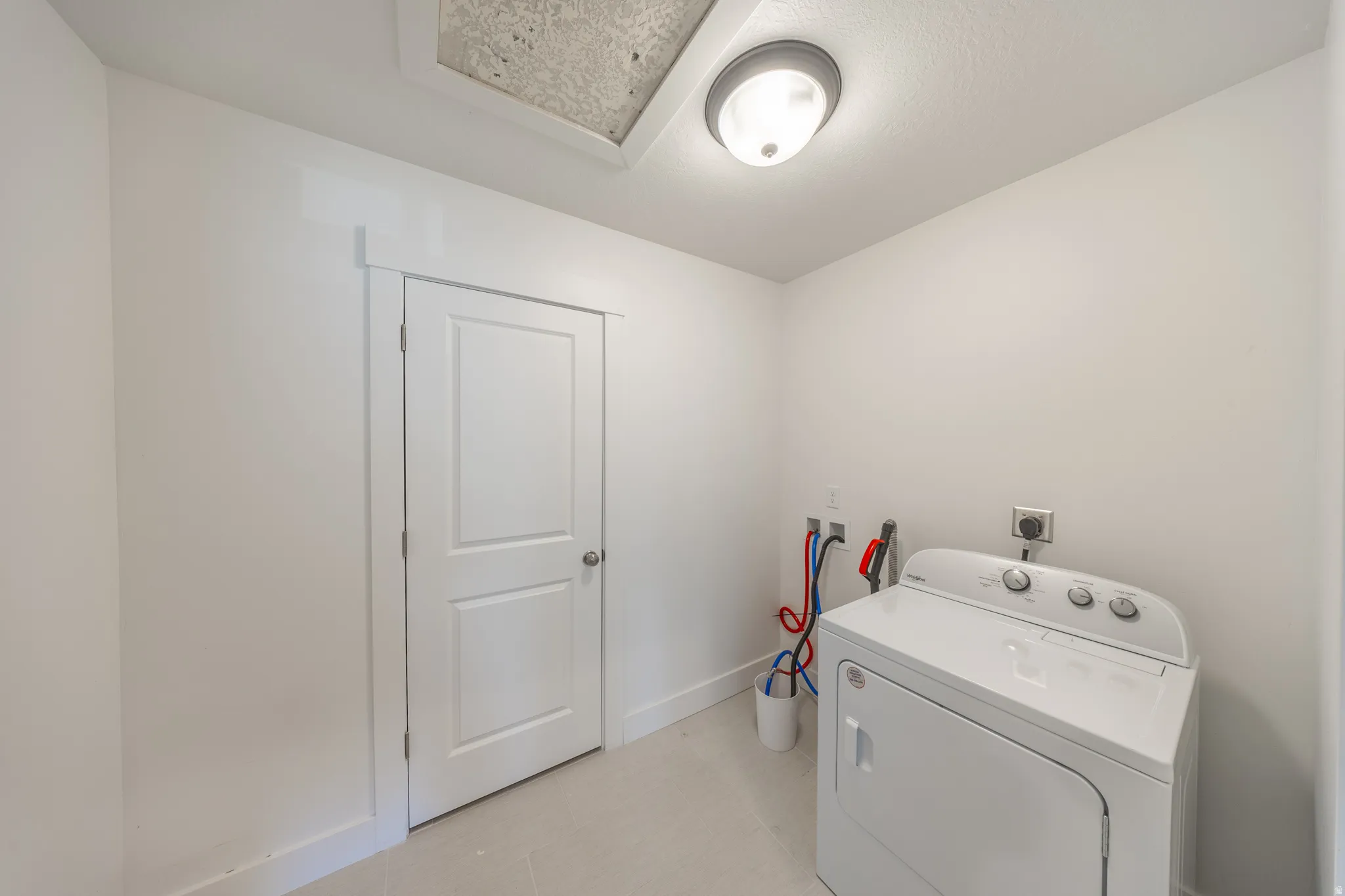 Dedicated laundry area featuring a white appliance, wall-mounted utility connections, and a ceiling-mounted light fixture