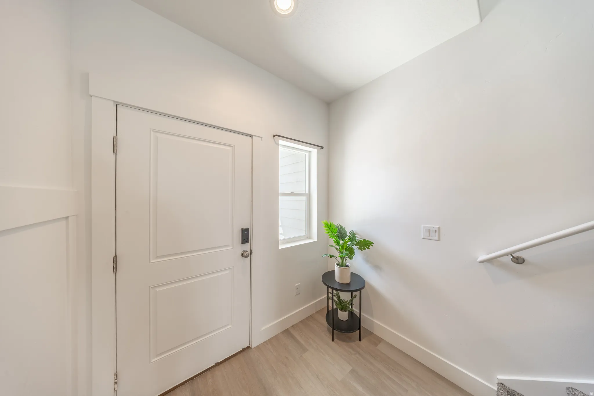 Entryway featuring a panel door with smart lock, wood-finish flooring, and natural light from a window