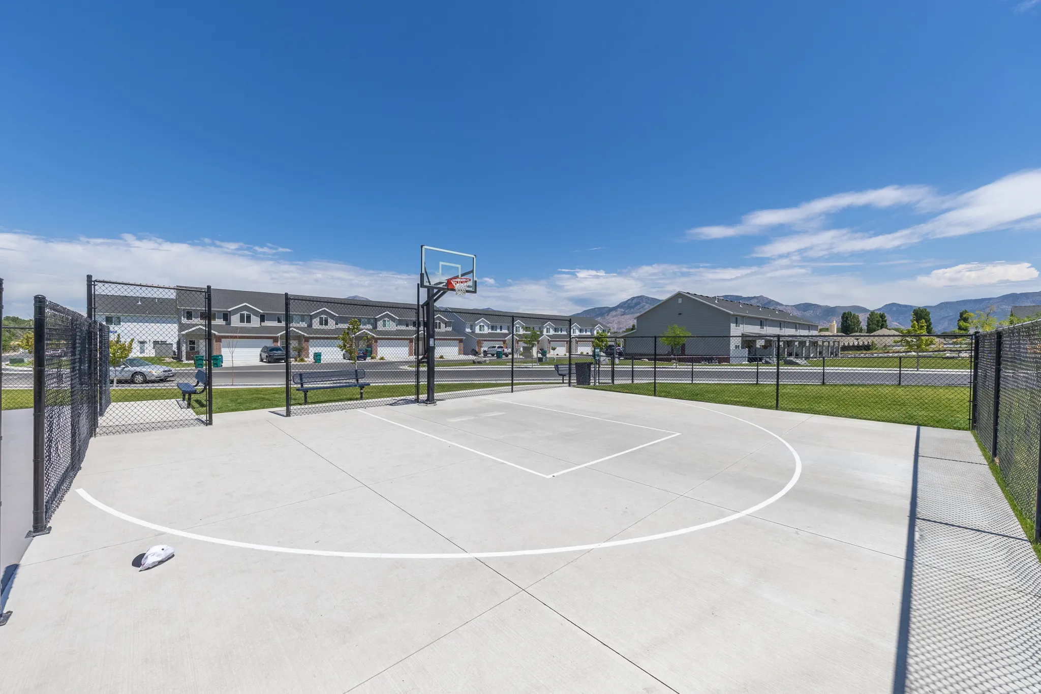 Outdoor basketball court with a chain-link fence enclosure