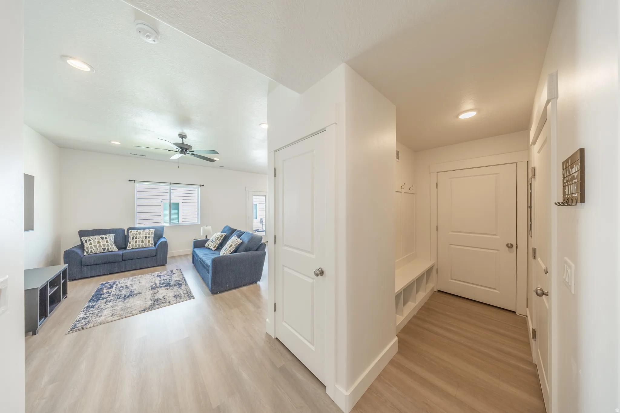 Open-concept living area with wood-finish flooring, recessed lighting, and a ceiling fan