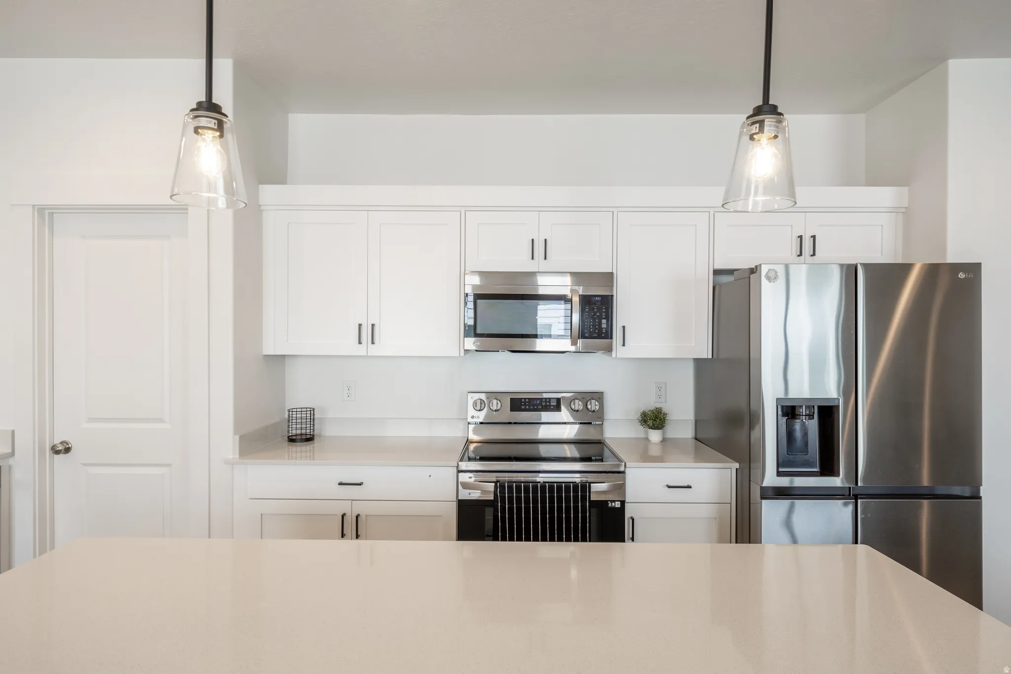 Contemporary kitchen featuring white shaker cabinetry and light-toned countertops