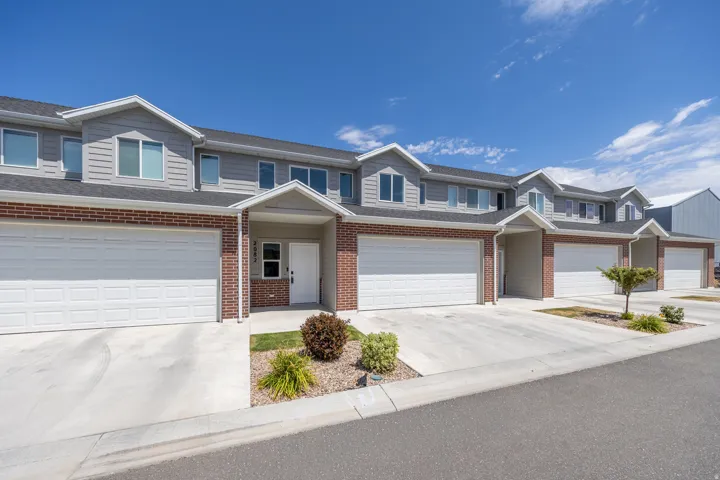 Townhome exterior featuring brick and horizontal siding, individual garages, covered entryways, and concrete driveways
