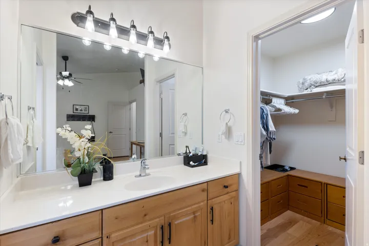 Bathroom vanity featuring a light-colored countertop, wood-finish cabinetry, and a large mirror with overhead lighting