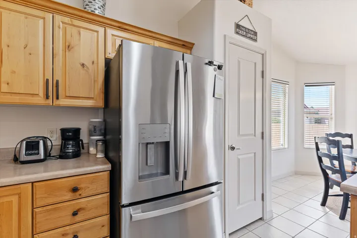 Kitchen area featuring a stainless steel French door refrigerator with an ice and water dispenser, light wood cabinetry, and a neutral countertop