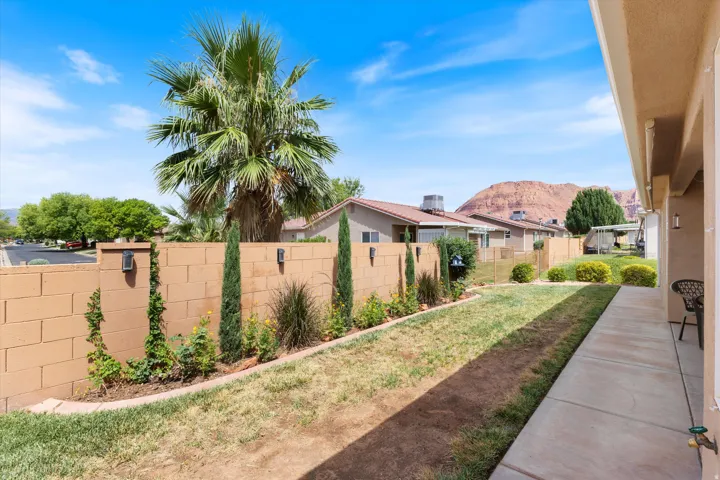 Expansive backyard featuring a concrete patio, a manicured lawn, and a block wall perimeter