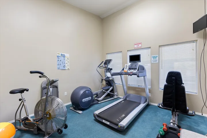 Dedicated exercise room featuring light beige walls and a high ceiling