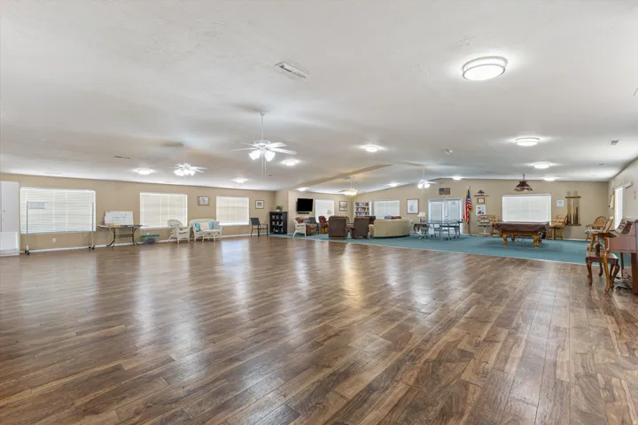 Spacious common area featuring wood-finish flooring, ample natural light from multiple windows, recessed lighting, and ceiling fans