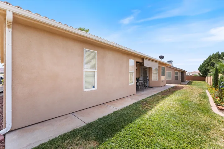 Expansive side yard featuring a manicured lawn, concrete pathway, and mature landscaping