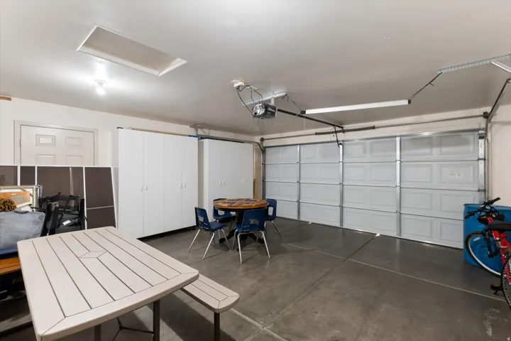 Spacious garage featuring a concrete floor, overhead lighting, and built-in storage cabinets