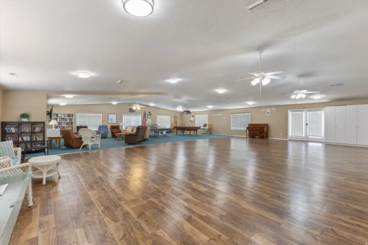 Expansive common area featuring wood-finish flooring, recessed lighting, and multiple ceiling fans