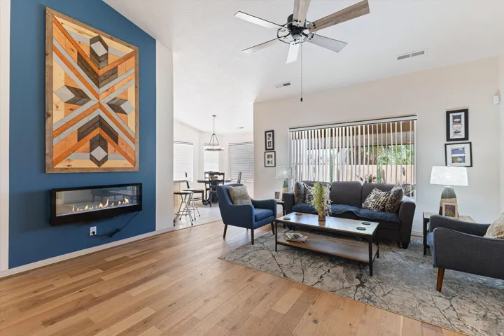 Spacious living area featuring light wood-finish flooring, a contemporary electric fireplace, and vaulted ceilings