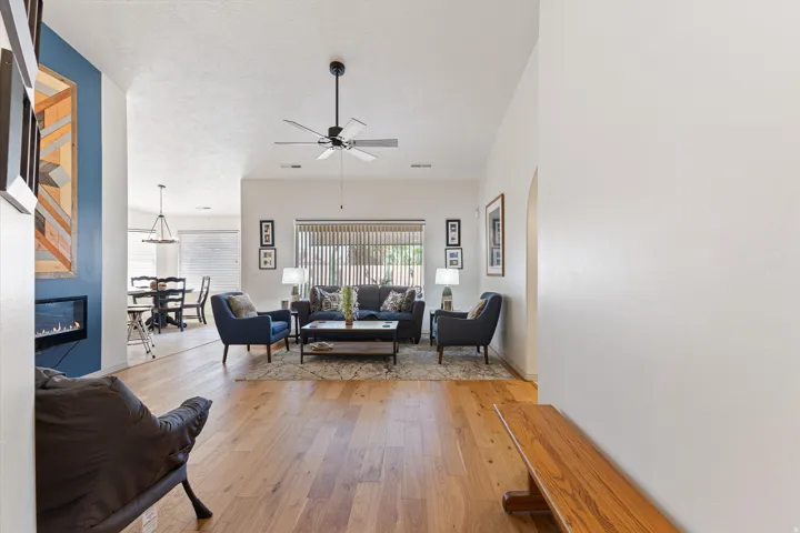Spacious living area featuring wood-finish flooring, a contemporary electric fireplace, and a ceiling fan