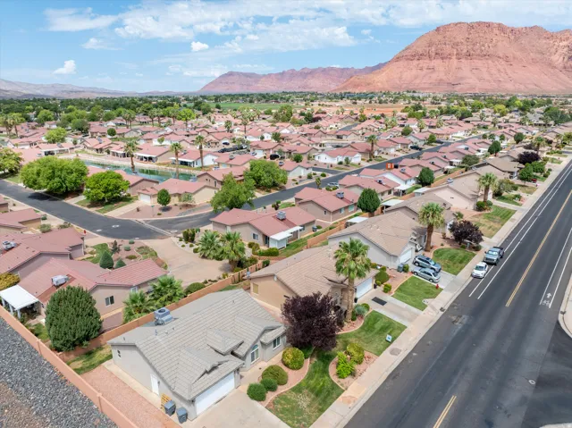 Suburban neighborhood with mature landscaping, a central water feature, and mountain backdrop