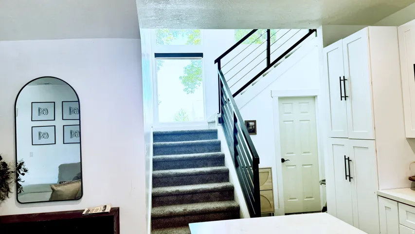 Staircase featuring carpeted treads, contemporary black metal railing, and a large window