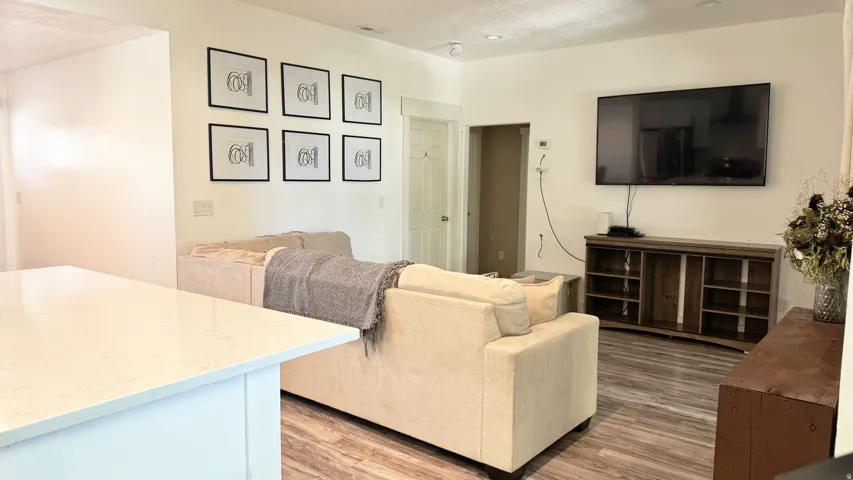 Open-concept living space featuring wood-finish flooring, recessed lighting, and a neutral color palette