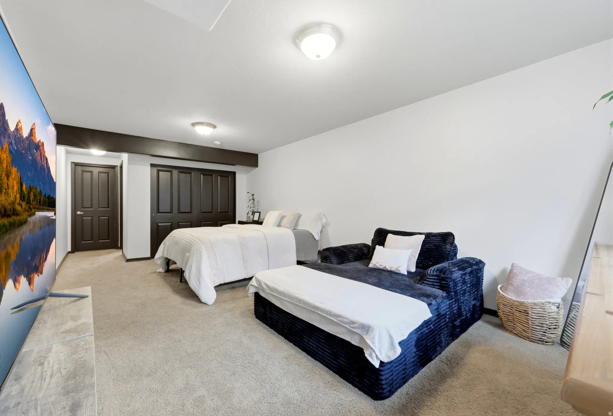 Spacious room featuring neutral carpeting, a dark wood-finish beam, and white walls