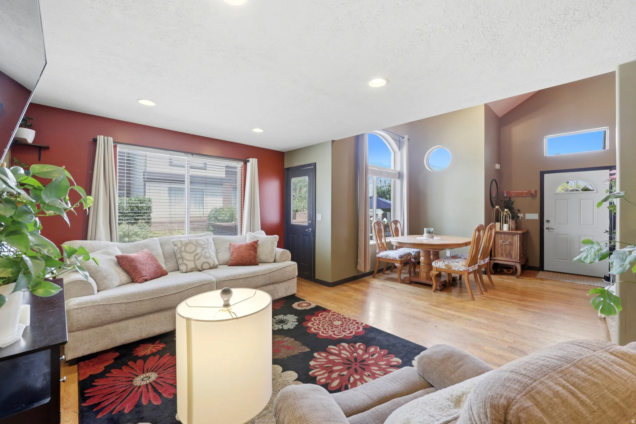 Living area featuring wood-finish flooring, recessed lighting, and a white front entry door with an arched window