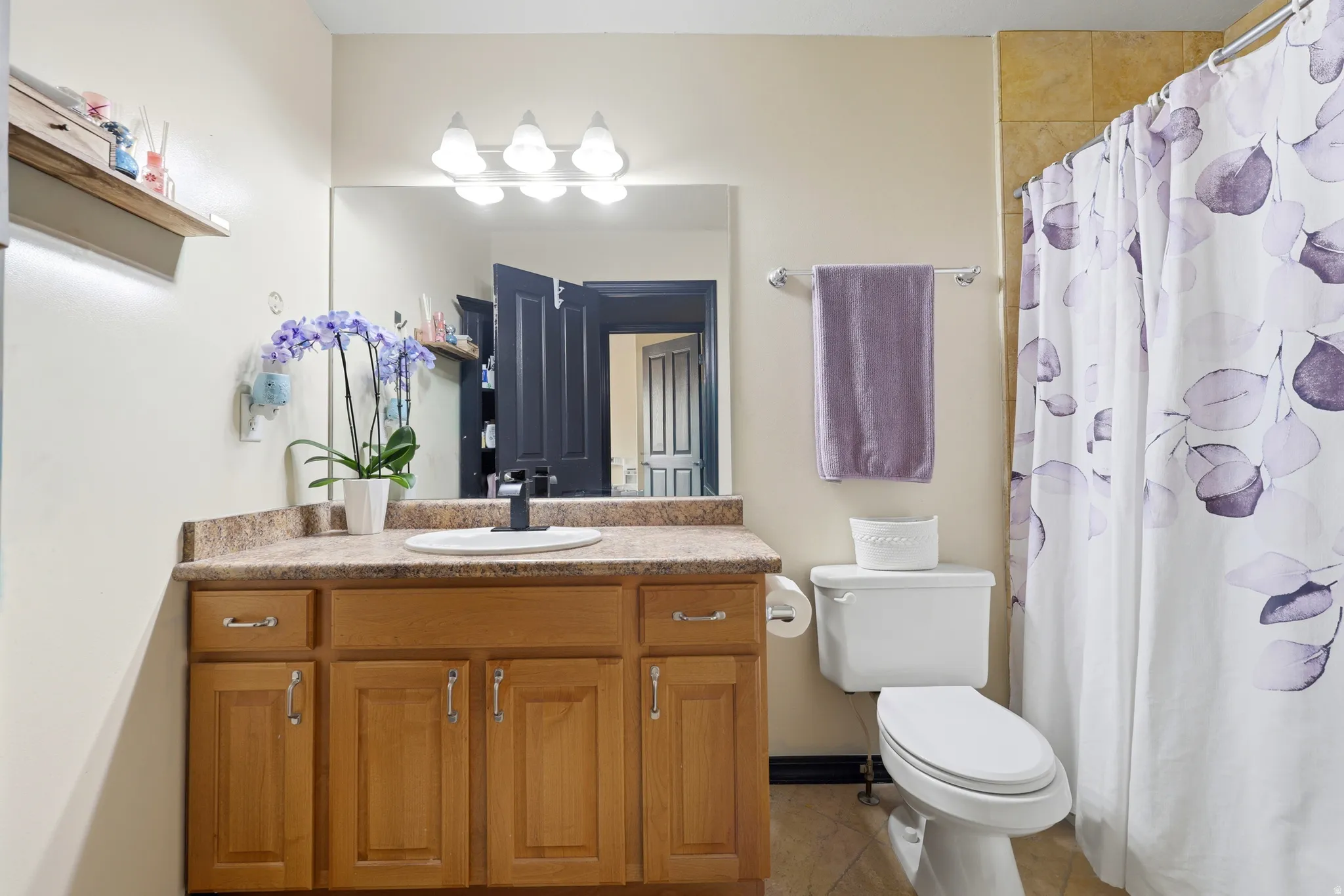 Bathroom featuring a wood-finish vanity with a built-in sink and a speckled countertop