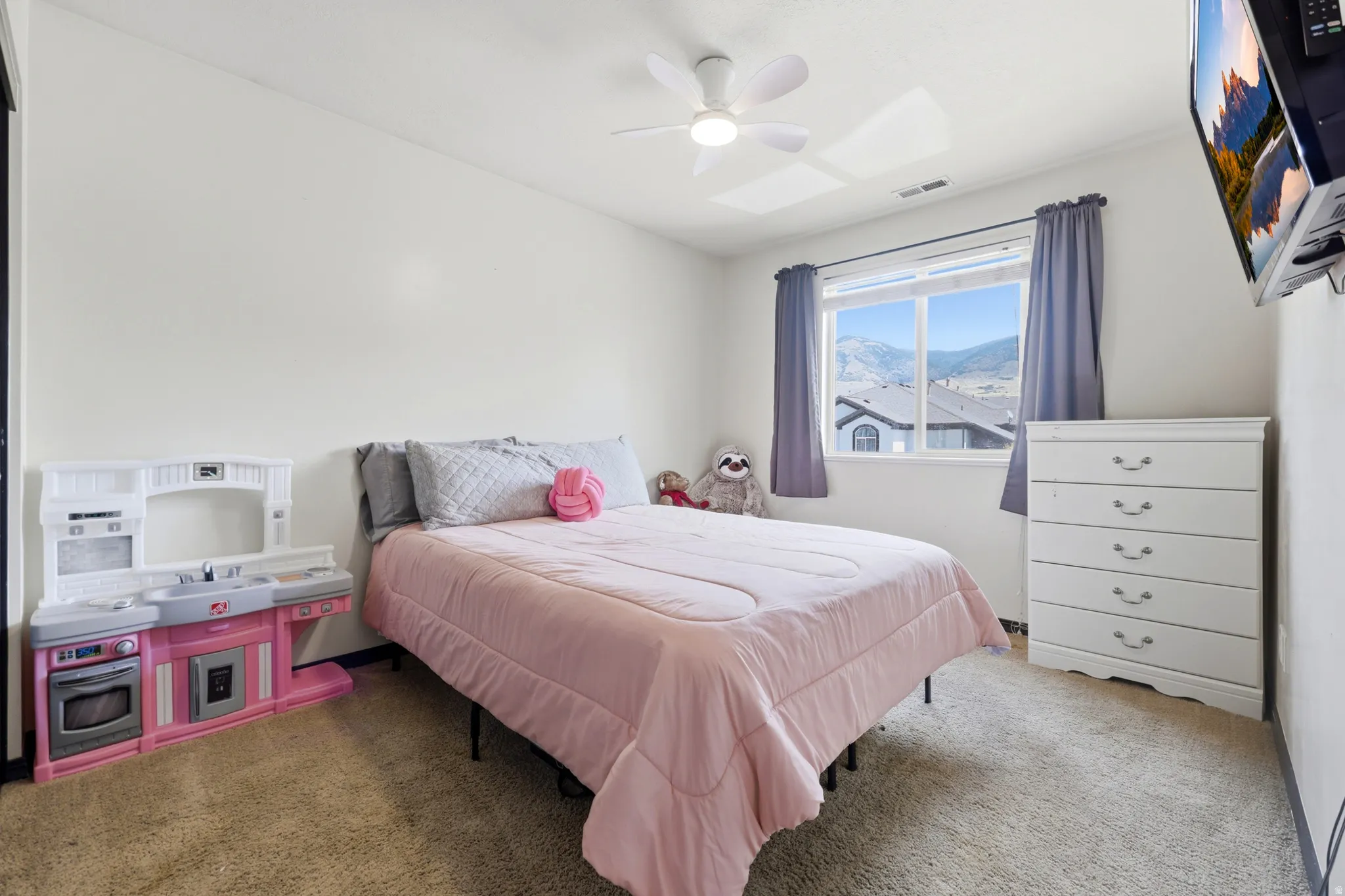 Carpeted room featuring a white ceiling fan, a window with mountain scenery, and light-colored walls