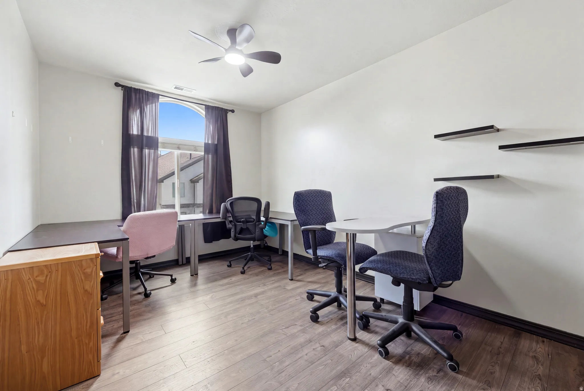 Room featuring wood-finish flooring, white walls, and a ceiling fan with integrated lighting