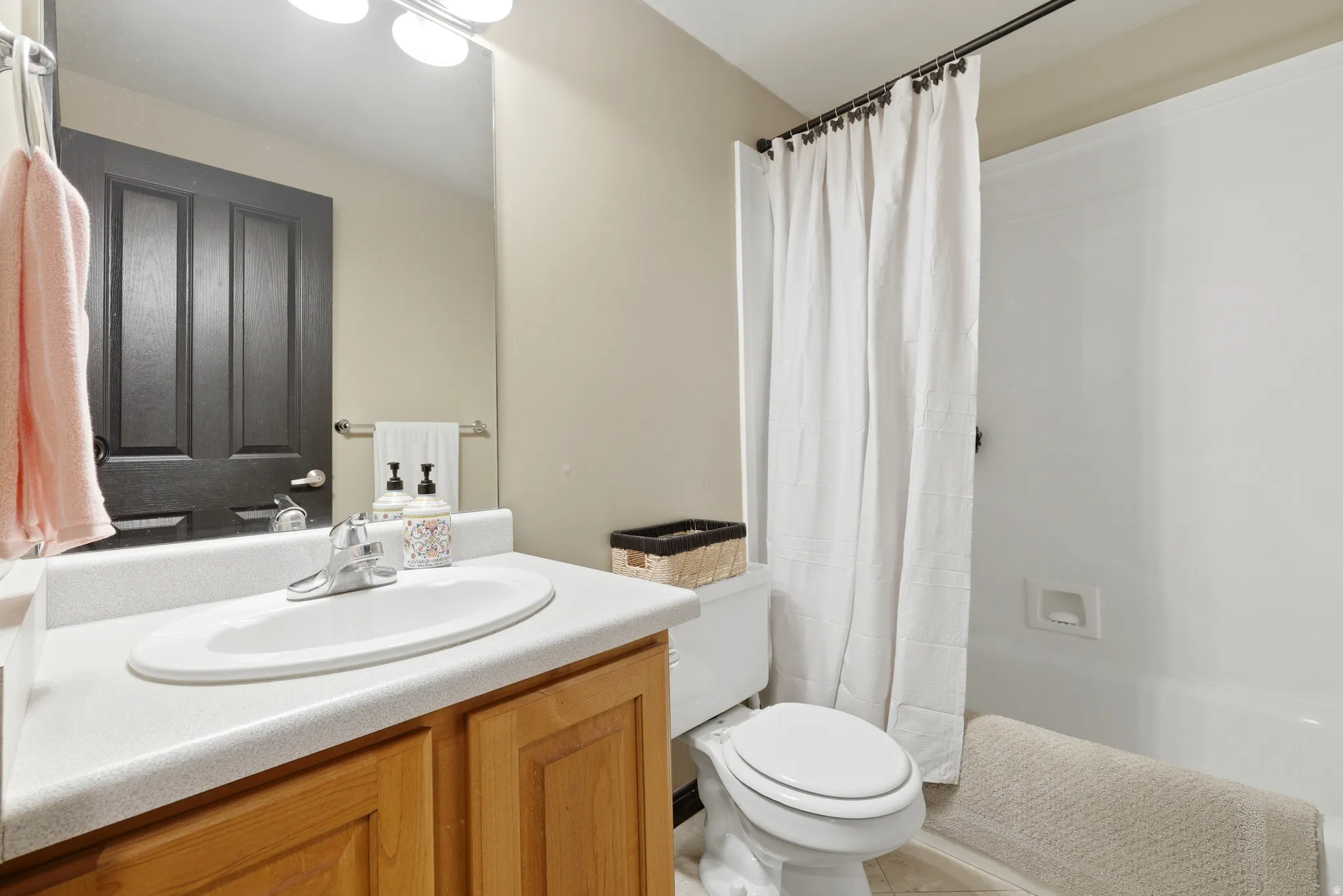 Bathroom vanity featuring a light wood-finish cabinet with a white countertop and integrated sink, complemented by a chrome faucet