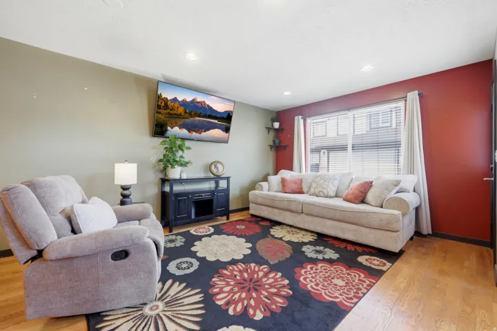 Living area featuring wood-finish flooring, recessed lighting, and a large window with blinds