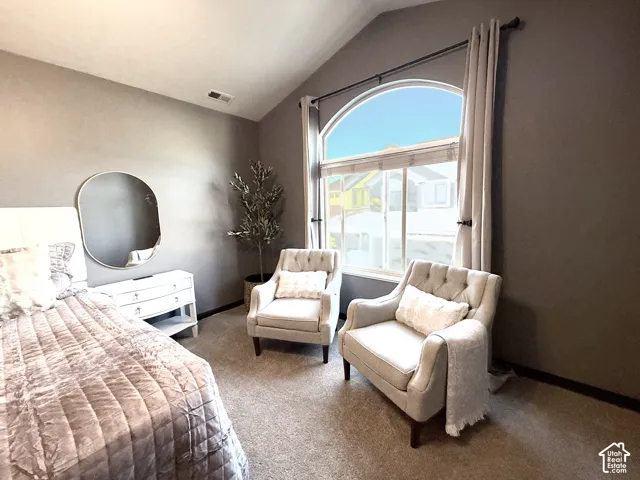 Vaulted ceiling featuring an arched window with integrated molding, neutral wall color, and wall-to-wall carpeting