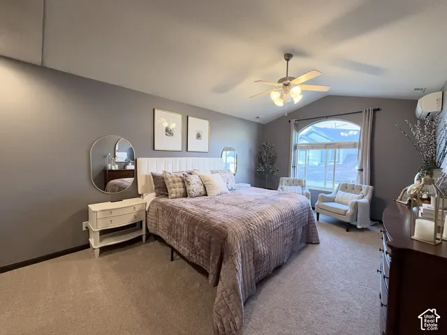 Room featuring vaulted ceilings, neutral-toned walls, arched window, wall-mounted heating and cooling unit, and a ceiling fan with integrated light fixture