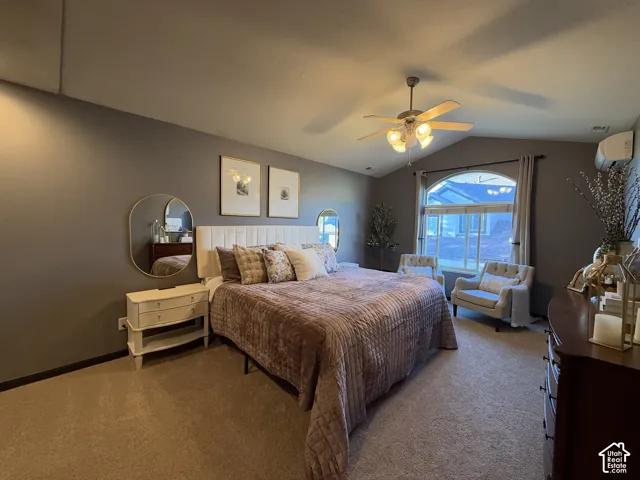 Very spacious primary bedroom with arched window, wall-mounted ductless heating and cooling unit, carpeted flooring, and ceiling fan with integrated lighting