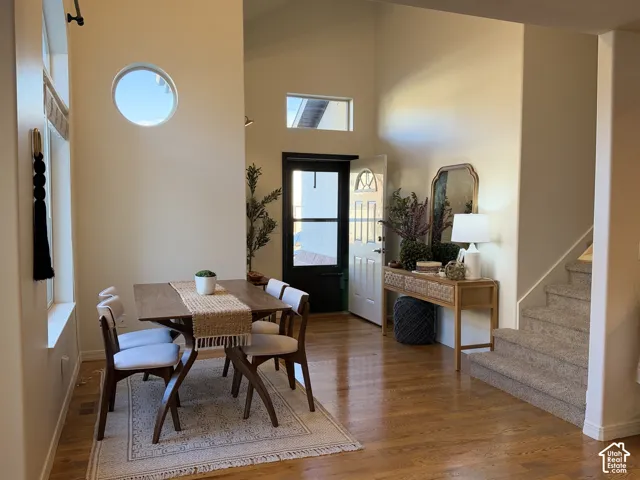 Vaulted ceilings featuring a circular accent window, transom window, wood-finish flooring, and carpeted staircase